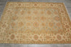 Load image into Gallery viewer, A rectangular area rug with an intricate floral and vine pattern, featuring a beige center, muted green-gray background, and rust-orange borders, laid out on a gray tiled floor.