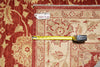 Load image into Gallery viewer, A close-up of a patterned area rug with a red border and beige floral field, shown with a yellow tape measure and a small handwritten tag reading 10039.