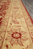 Load image into Gallery viewer, A close-up view of a traditional patterned area rug with a warm beige background and red floral motifs, shown on a gray floor.