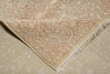 Load image into Gallery viewer, A close-up of a beige and cream patterned rug, showing the corner with fringed edges and detailed floral motifs.