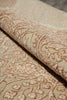 Load image into Gallery viewer, A close-up of a beige and tan patterned rug with a rolled section showing the raised floral and vine texture.