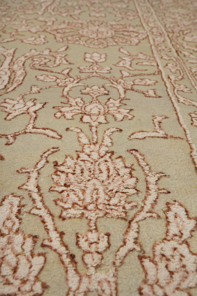 Close-up of a traditional patterned area rug with an ornate floral and vine design in beige and light brown tones.