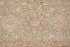 Load image into Gallery viewer, A close-up of a traditional patterned rug featuring a central medallion and floral motifs in dusty pink and beige on a muted sage green background.