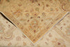Load image into Gallery viewer, A close-up of a traditional patterned area rug with a folded corner showing its texture and fringed edge. The rug features a warm beige and cream base with intricate floral motifs in muted brown, green, and rust tones.