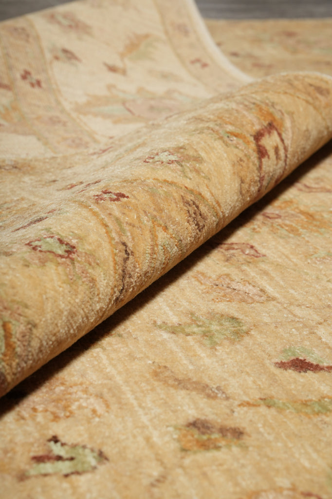A close-up of a rolled area rug showing its textured, low-pile surface with a subtle beige and tan floral pattern.