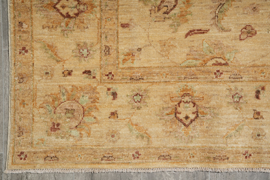 A close-up of a traditional oriental rug with a warm beige base, featuring faded floral motifs and geometric borders in muted brown, green, and rust tones.