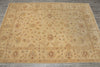 Load image into Gallery viewer, A large rectangular area rug with an intricate traditional floral and medallion pattern in warm beige, tan, and muted brown tones, laid out on a gray tiled floor.