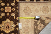 Load image into Gallery viewer, A close-up of a traditional oriental rug with a dark brown floral pattern on the left and a beige section on the right, shown with a yellow tape measure and a price tag.