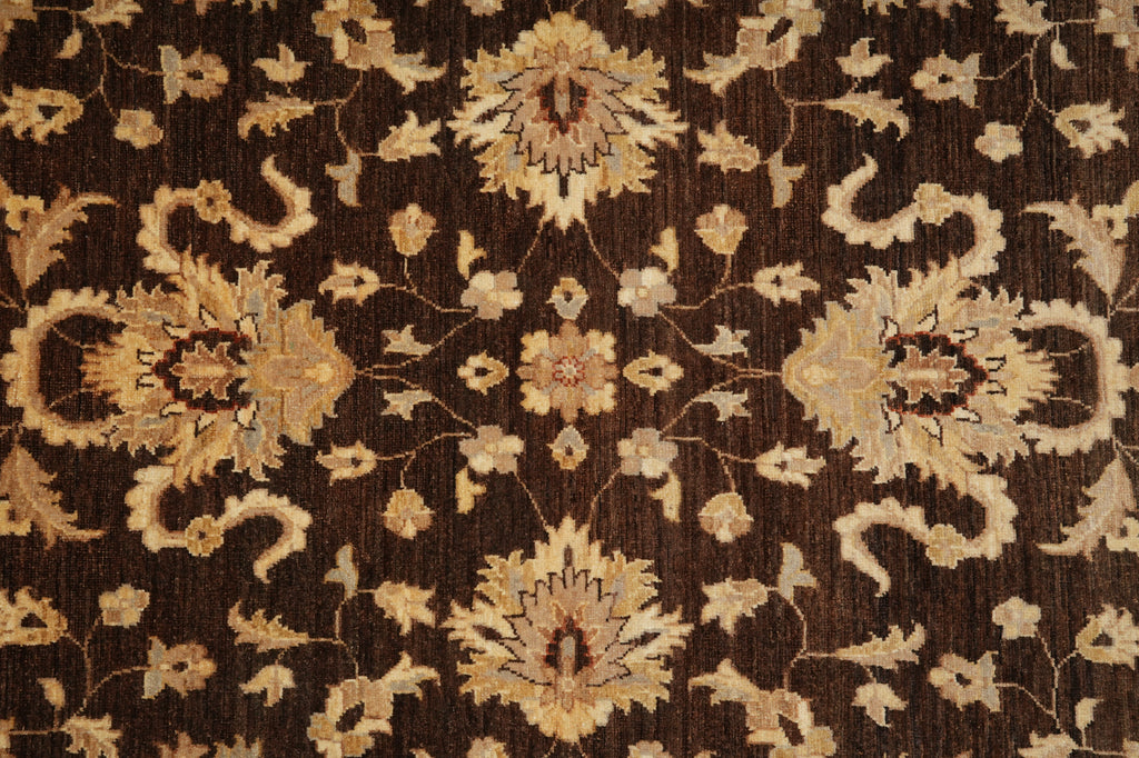 A close-up of a dark brown rug with an ornate beige and cream floral pattern.