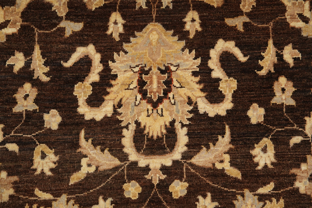 A close-up of an ornate damask-style rug pattern in dark brown with beige and cream floral motifs.
