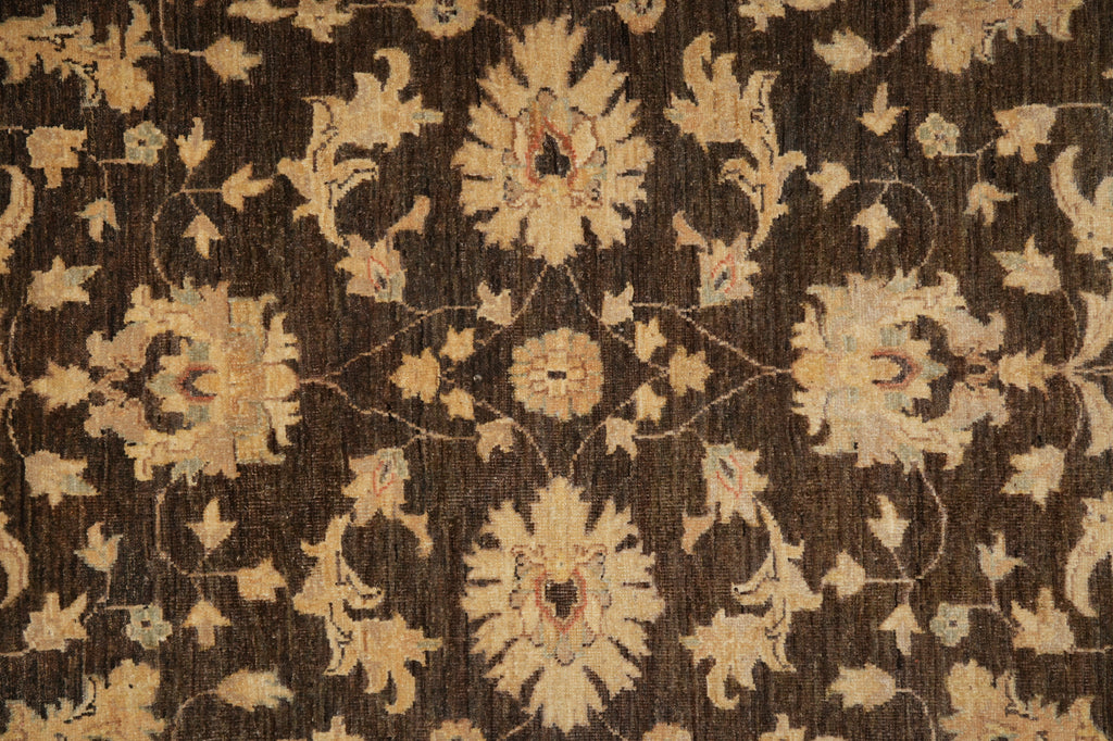 A close-up of an ornate floral patterned rug with a dark brown background and beige, tan, and muted red motifs.