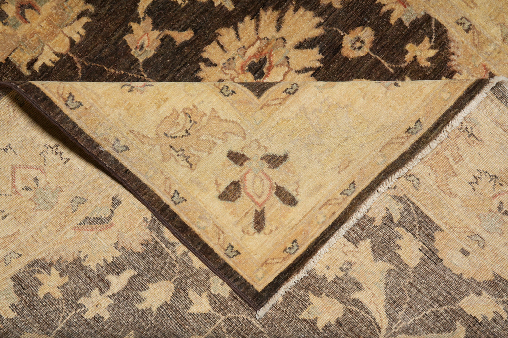 A close-up of an ornate patterned rug showing a folded corner that reveals a beige center with dark brown floral motifs and a dark brown border, layered over another section of the rug with a gray and beige floral design.