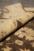 Load image into Gallery viewer, A close-up of a rolled area rug showing its textured beige and brown floral pattern, laid over another matching rug on a dark wood floor.