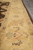 Load image into Gallery viewer, A close-up view of a traditional area rug with a warm beige and yellow base, featuring faded floral and geometric motifs in brown, muted red, and soft green.