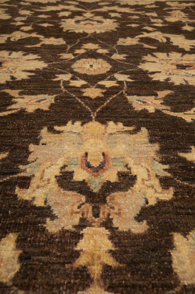 A close-up of a traditional patterned rug with a dark brown base and beige floral motifs, accented with subtle muted blue and red details.
