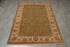 Load image into Gallery viewer, A rectangular area rug with an ornate floral medallion pattern, featuring a muted olive green center field and beige borders, laid out on a gray wood-look floor.