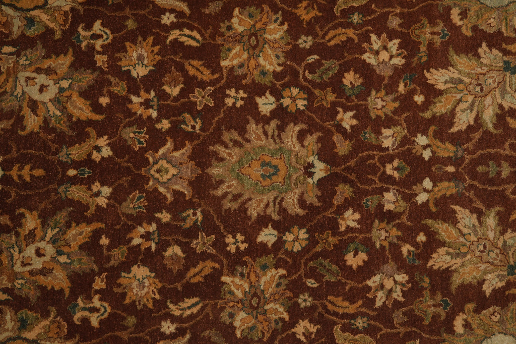 A close-up of a traditional patterned rug with a dark brown background and beige, tan, and muted green floral motifs.