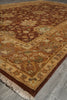 Load image into Gallery viewer, An ornate traditional area rug with a floral pattern, featuring a dark brown center, golden-beige borders, and cream fringe, laid out on a gray tiled floor.