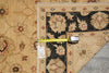 Load image into Gallery viewer, A close-up of a patterned area rug corner with a yellow tape measure laid across it and a product tag hanging from the tape. The rug has a beige base with a dark navy floral pattern and muted rust accents.
