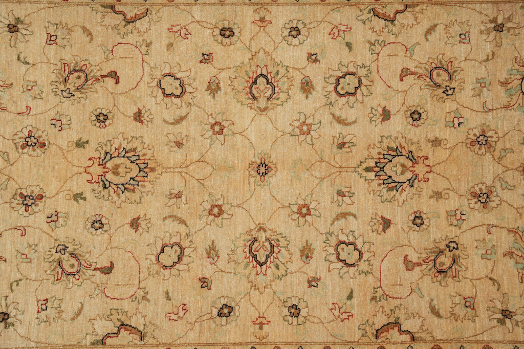 An antique floral patterned rug in beige with red, blue, and green accents, showing detailed woven texture and traditional motifs.
