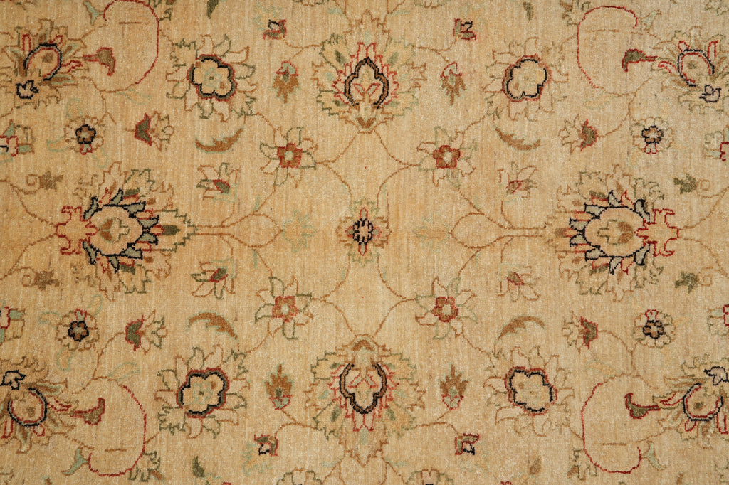 A close-up of a vintage-style floral rug with an intricate symmetrical pattern in beige, rust red, and dark brown.