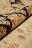 Load image into Gallery viewer, A close-up of a traditional patterned area rug with a rolled section showing the detailed pile and design. The rug features a beige base with black, brown, and red accents in an ornate floral and geometric motif.