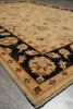 Load image into Gallery viewer, A close-up view of a traditional area rug with a beige field, a wide black border, and floral motifs in cream, rust, and olive, shown on a gray floor.