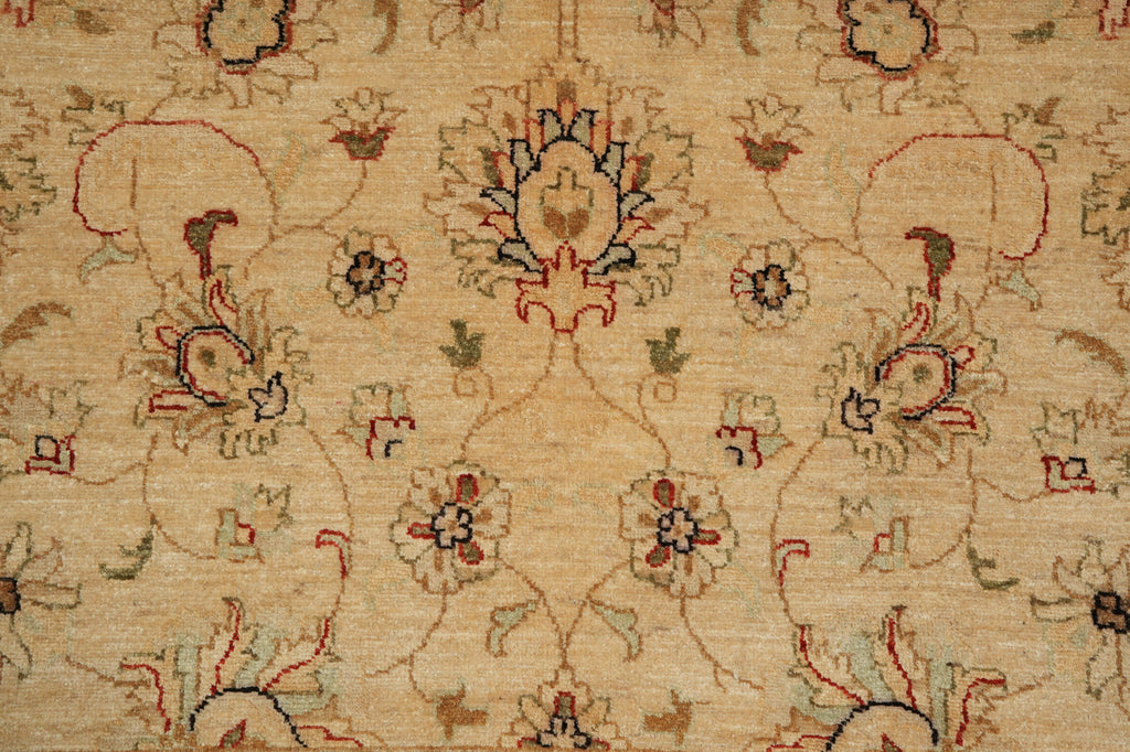 A close-up of a traditional patterned rug with a beige background and intricate floral motifs in muted red, green, and brown.