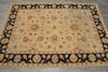 Load image into Gallery viewer, A rectangular vintage-style area rug with a beige center field and a wide black border, featuring intricate floral and medallion motifs in beige, brown, and muted red, laid out on a gray floor.