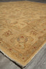 Load image into Gallery viewer, A close-up view of a traditional area rug with a warm beige and tan base, featuring faded floral motifs and small red accents, laid out on a gray wood floor.