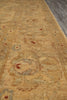 Load image into Gallery viewer, A close-up view of a traditional area rug with a warm beige and gold base, featuring faded blue-gray floral motifs and small rust-red accents.