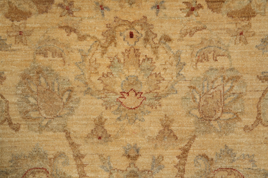 A close-up of a textured area rug featuring a traditional floral and botanical pattern in muted beige, tan, and dusty red tones.