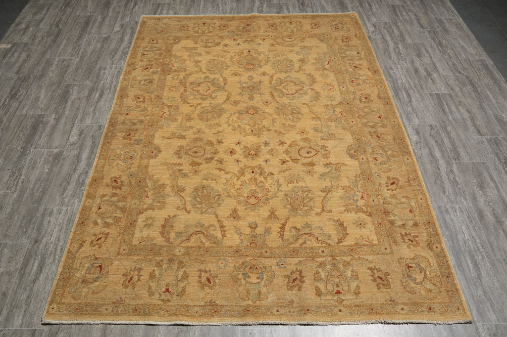 A rectangular area rug with an ornate traditional floral pattern in warm beige, tan, and muted rust red tones, shown flat on a gray wood-look floor.