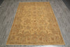 Load image into Gallery viewer, A rectangular area rug with an ornate traditional floral pattern in warm beige, tan, and muted rust red tones, shown flat on a gray wood-look floor.