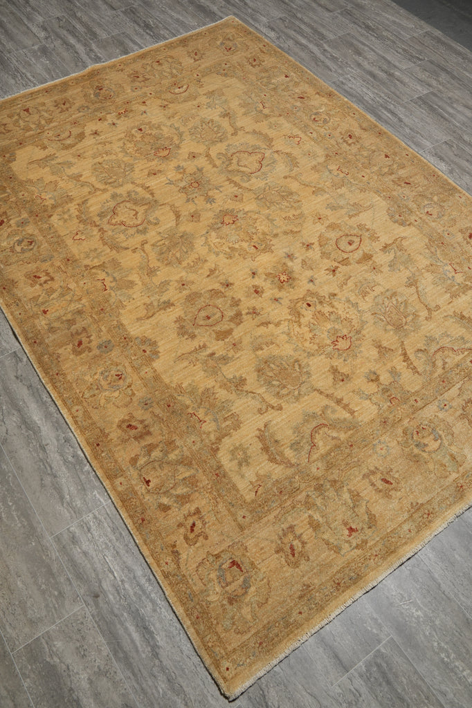 A rectangular area rug with an intricate traditional floral pattern in beige, tan, and muted red, shown from an elevated angle on a gray wood-look floor.