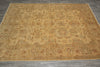 Load image into Gallery viewer, A large rectangular area rug with an intricate traditional floral and medallion pattern in warm beige, tan, and muted rust red tones, laid out on a gray tiled floor.