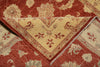 Load image into Gallery viewer, A close-up of a folded area rug showing its pattern and texture. The rug features a deep red field with a cream-colored central diamond panel and floral motifs, bordered by a red and cream patterned edge.