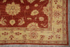 Load image into Gallery viewer, A close-up of a traditional patterned rug showing a deep red field with beige floral motifs and a beige border with red detailing.