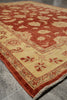 Load image into Gallery viewer, A traditional oriental-style area rug with a warm rust red and beige floral pattern, shown laid out on a gray tiled floor.
