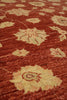 Load image into Gallery viewer, A close-up of a textured area rug featuring a warm rust red background with a repeating floral pattern in a light beige color.