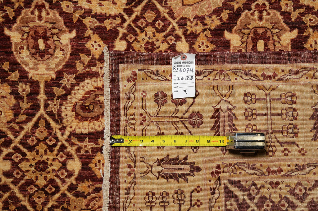 A close-up of a patterned area rug with a beige center and dark brown borders, shown with a yellow tape measure and a small product tag on top.