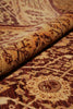 Load image into Gallery viewer, A close-up of a patterned area rug with one corner rolled back, showing its woven texture and traditional floral motifs in beige, brown, and burgundy tones.