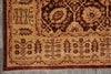 Load image into Gallery viewer, A close-up of an ornate traditional rug corner showing a beige and dark red pattern with floral motifs and a fringed edge on a gray floor.