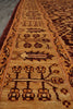 Load image into Gallery viewer, A close-up view of a traditional patterned area rug with a warm tan and brown base, featuring dark brown geometric and floral motifs.