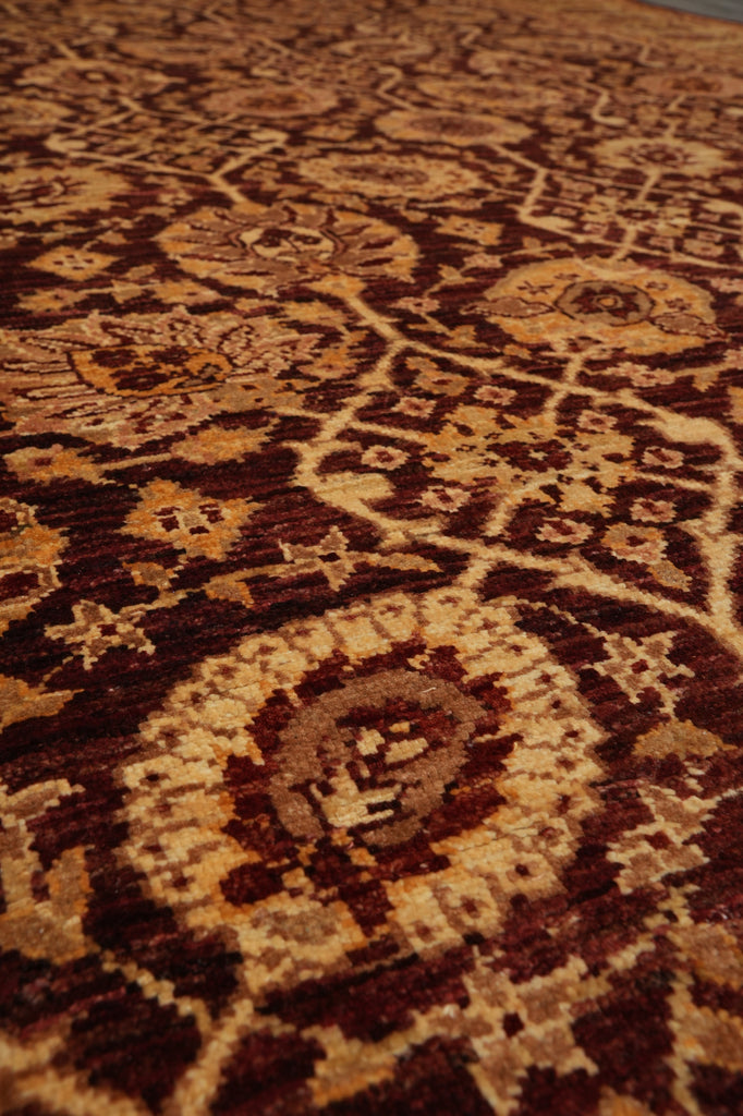 A close-up view of a traditional patterned area rug with intricate floral and geometric motifs in dark brown, rust red, beige, and cream.