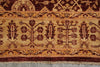 Load image into Gallery viewer, A close-up of a patterned rug showing a traditional design with floral motifs in dark red and brown on a warm beige background, with a fringed edge visible at the bottom.