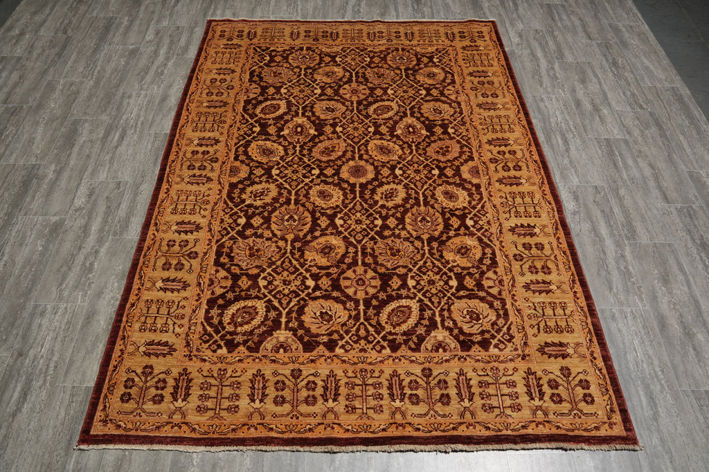 A rectangular traditional area rug with an intricate floral and geometric pattern in shades of brown, rust, and beige, laid out on a gray wood-look floor.