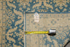 Load image into Gallery viewer, A close-up of a patterned area rug with a blue and beige floral design, shown with a yellow tape measure and a small inventory tag on top.