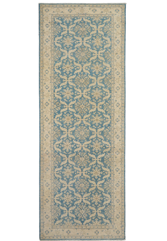 A long rectangular area rug with an ornate repeating floral and geometric pattern in muted blue and warm beige, shown flat against a plain white background.
