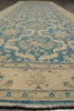 Load image into Gallery viewer, A close-up view of a traditional patterned area rug with a beige base and blue motifs, showing the woven texture and fringe detail.